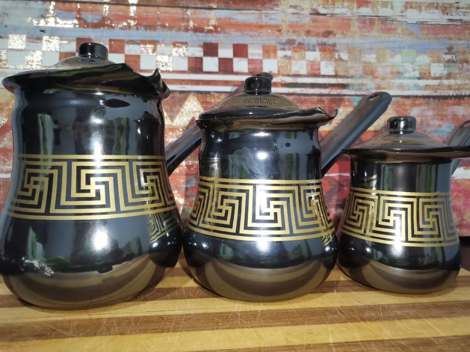cafetera con tapa, color negra con diseño de lineas doradas.